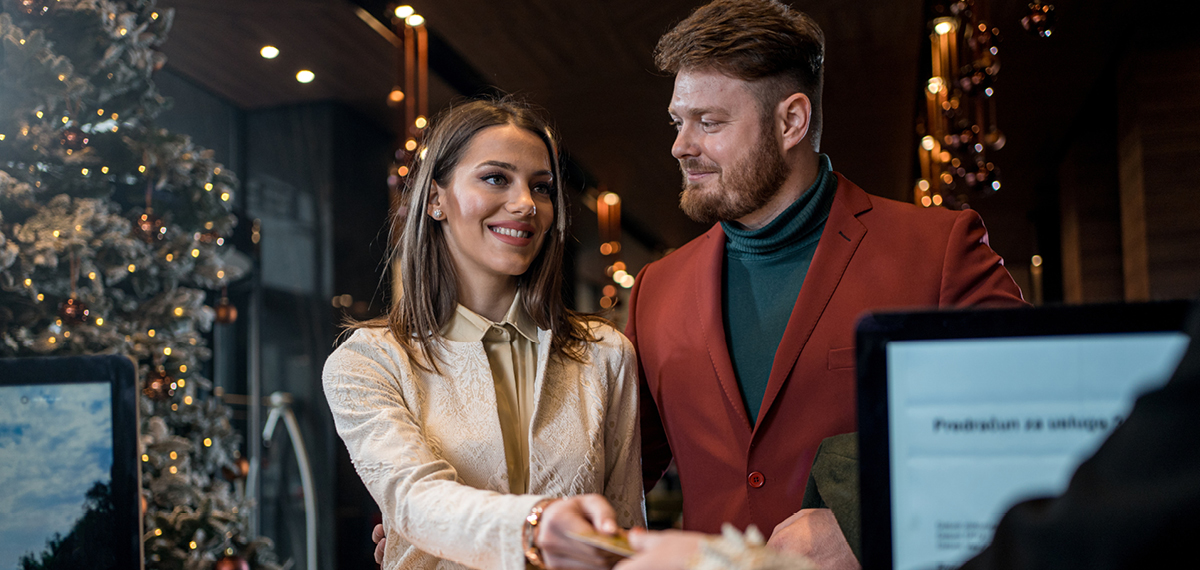 happy couple checking into a hotel during the cyber room sale